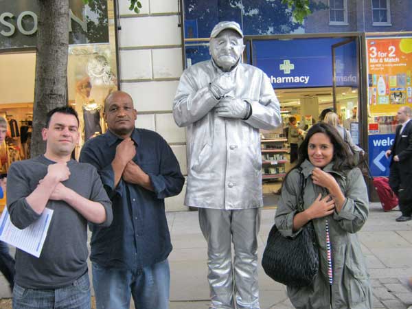 Three people posing with a human statue in Covent Garden.